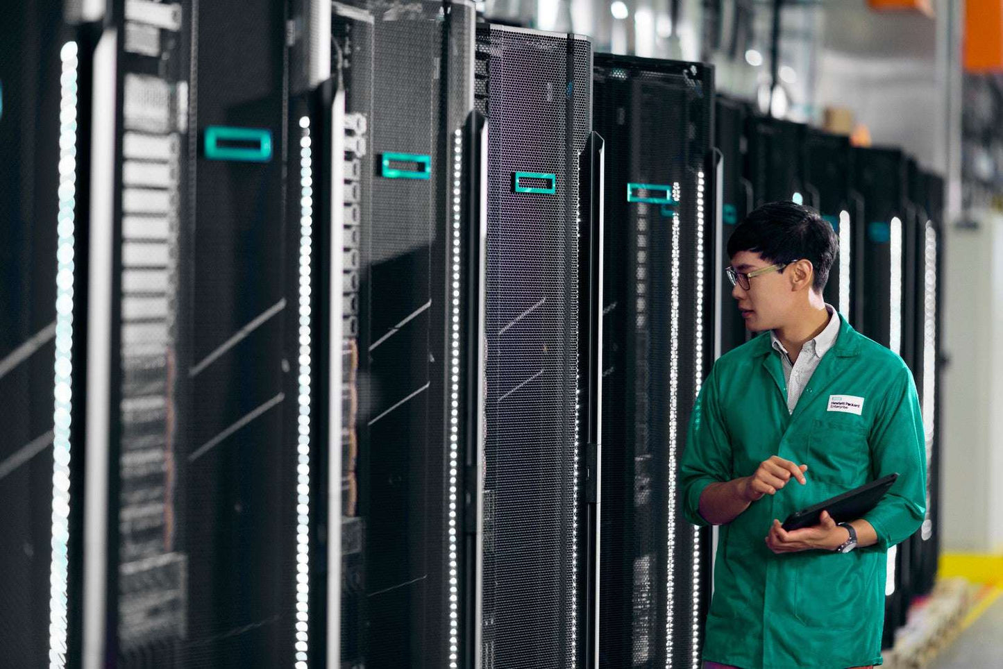 Man in green uniform by HPE ProLiant DL360 Gen11 server racks with LED lights