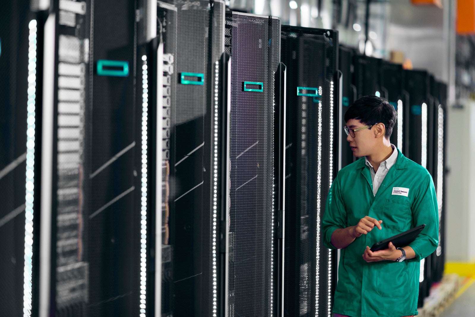 Man in green uniform by HPE ProLiant DL360 Gen11 server racks with LED lights